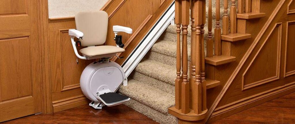stairlift at bottom of carpeted steps against wood paneled wall